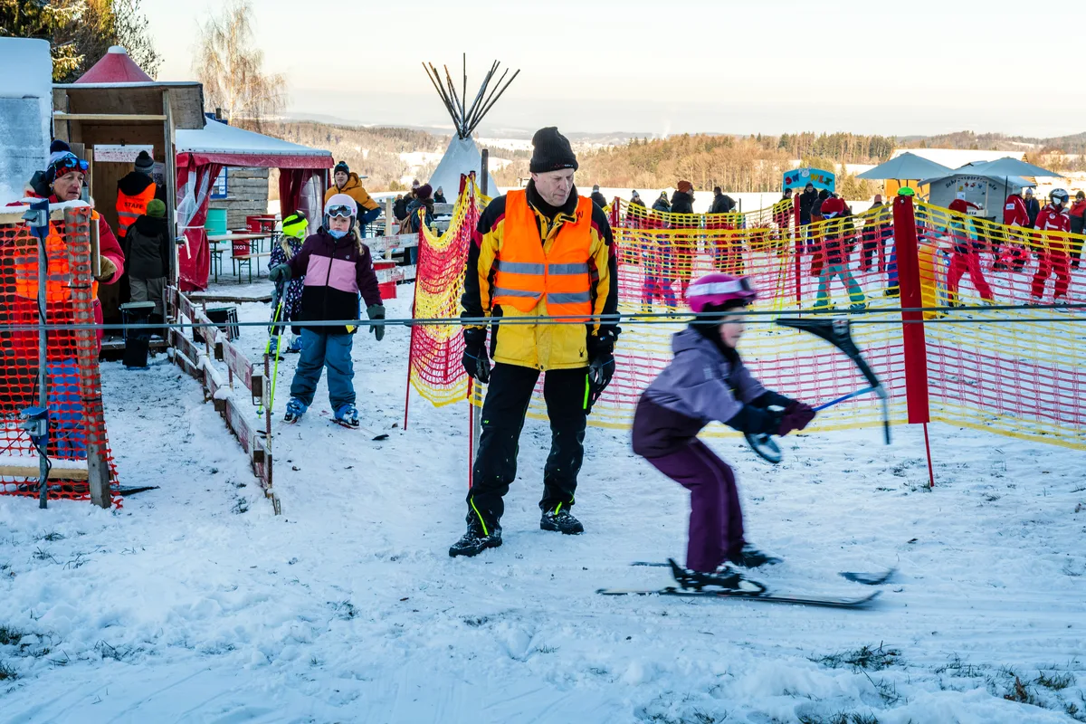 Man sieht einen Mann, der einen Skilift beaufsichtigt. 